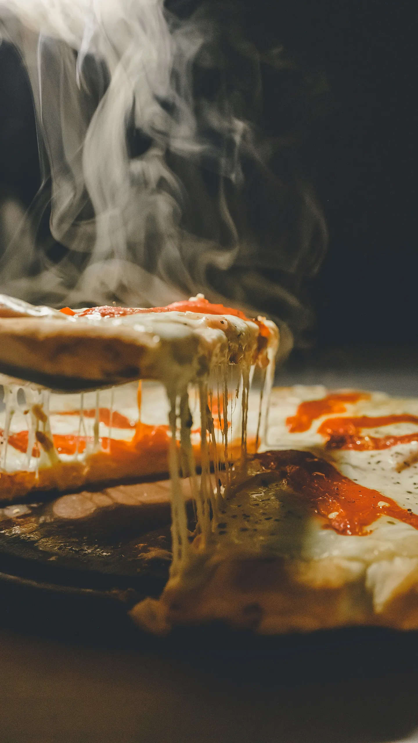 Parująca pizza prosto z pieca z ciągnącym się serem